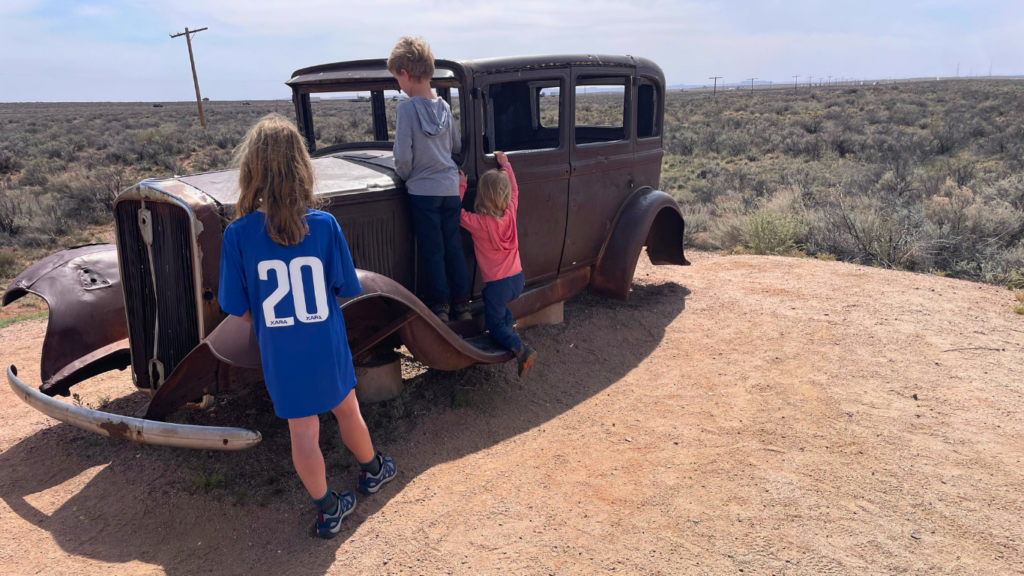 An old car in Petrified Forest with kids